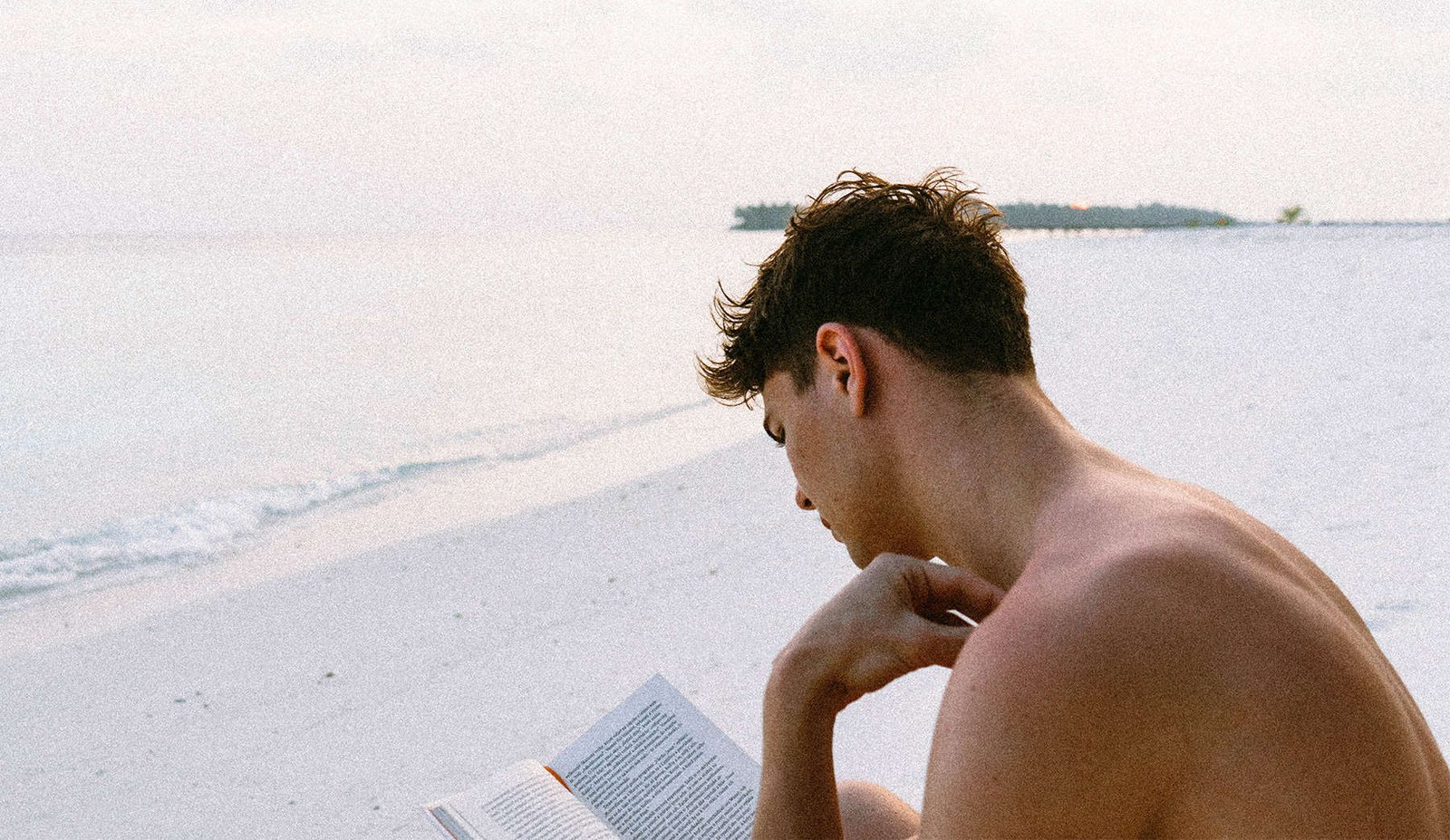 chico leyendo en la playa